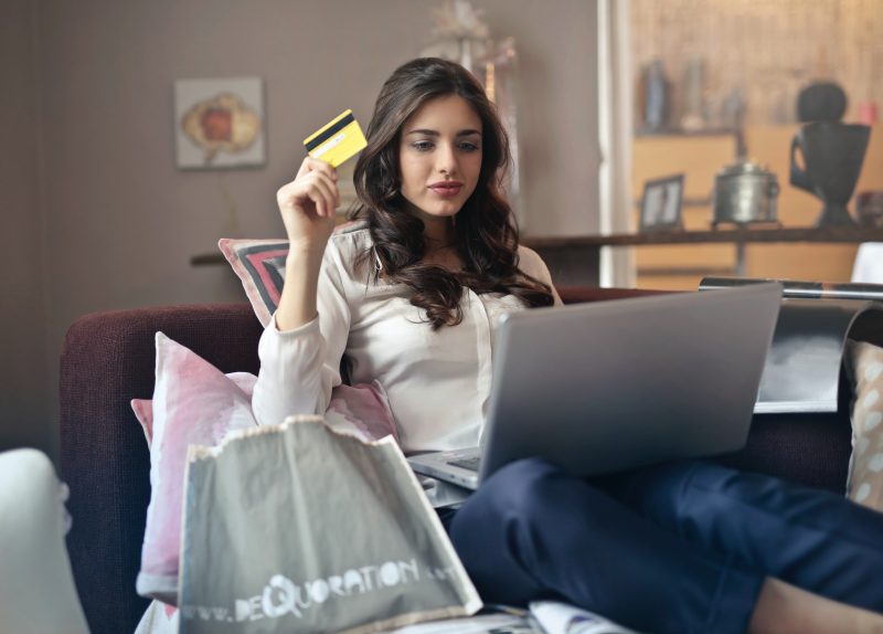 Femeie ţine un card în mână şi cumpără din magazinele online